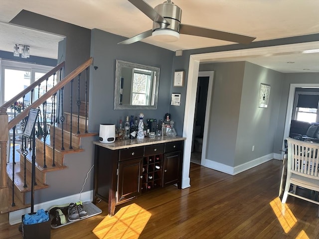 bar with a ceiling fan, baseboards, stairs, dark wood-style floors, and a dry bar