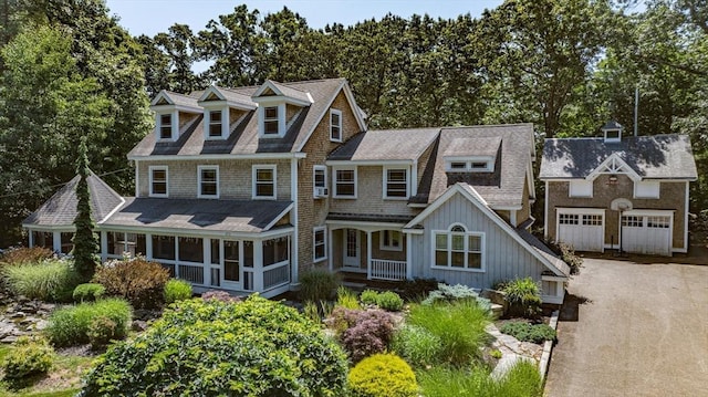 view of front of house featuring covered porch, board and batten siding, driveway, roof with shingles, and a sunroom