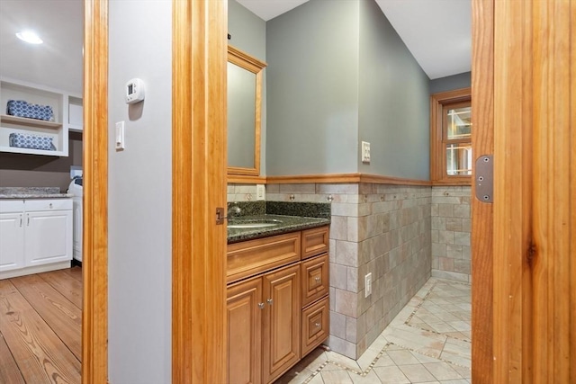 bathroom featuring vanity, wainscoting, and tile walls