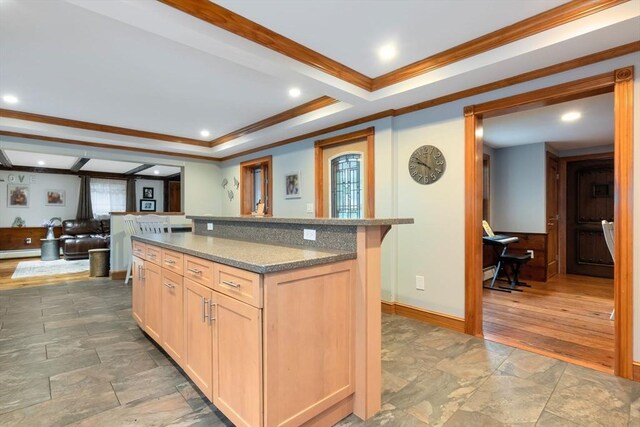 kitchen with light brown cabinetry, crown molding, a center island, stone tile floors, and a baseboard heating unit