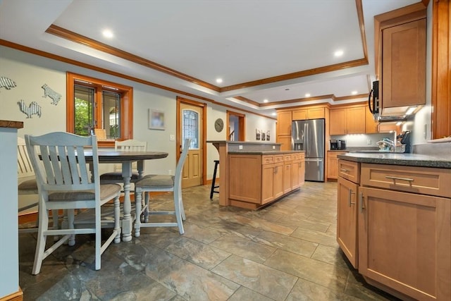 kitchen with crown molding, appliances with stainless steel finishes, a breakfast bar area, and a tray ceiling