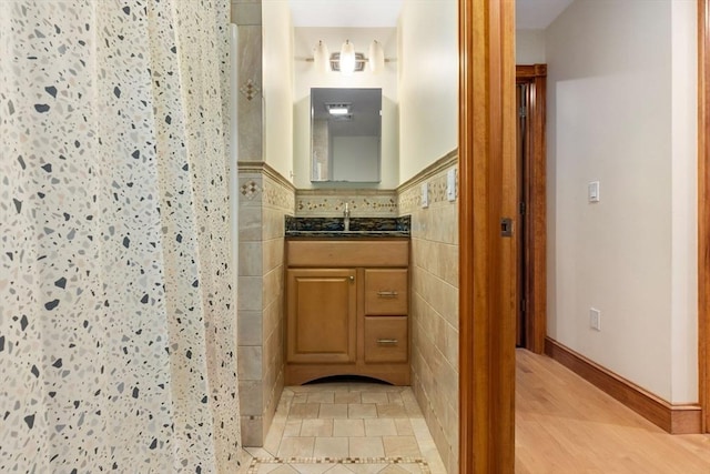 bathroom featuring vanity, a walk in shower, and tile walls