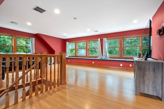 bonus room with plenty of natural light, light wood-style flooring, and visible vents
