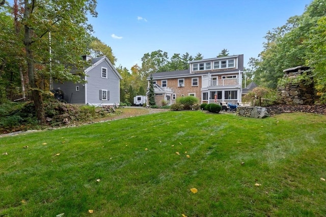 rear view of house featuring a yard and a balcony