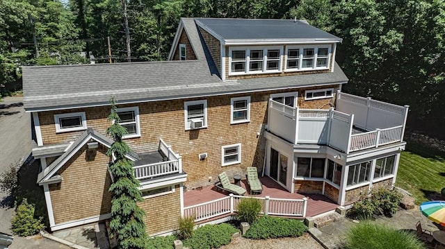 view of front facade with roof with shingles and a balcony