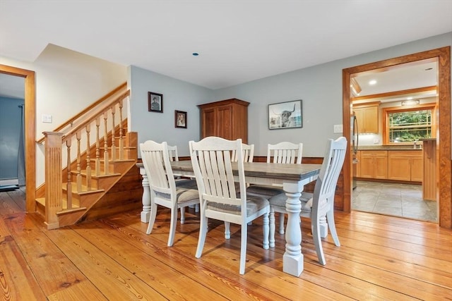 dining area featuring light wood finished floors and stairs