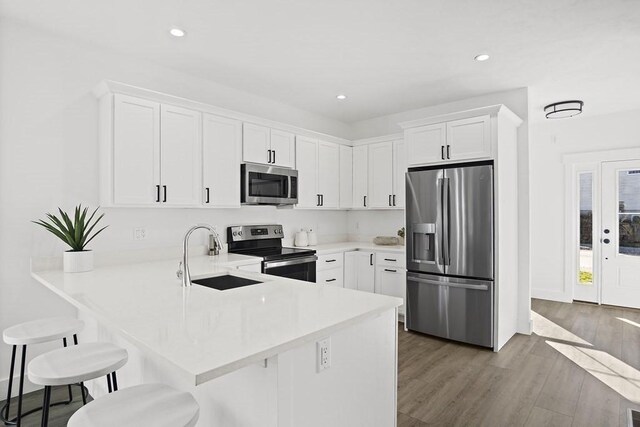 25 Salisbury Hill Blvd Unit 62, Worcester, MA 01609 - kitchen featuring a peninsula, wood finished floors, a sink, white cabinets, and appliances with stainless steel finishes