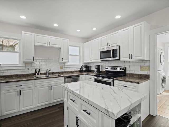 73 Laurel St, Leominster, MA 01453 - kitchen with a sink, appliances with stainless steel finishes, backsplash, and stacked washing maching and dryer