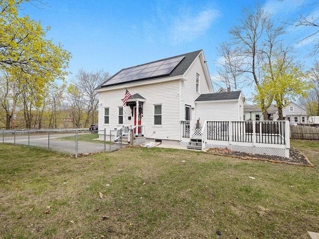 73 Laurel St, Leominster, MA 01453 - view of front facade featuring a shingled roof, a wooden deck, a front yard, roof mounted solar panels, and a fenced backyard