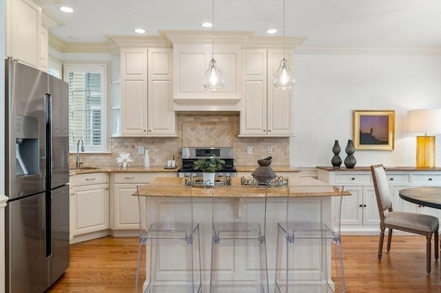 kitchen with light stone counters, ornamental molding, stainless steel appliances, light wood-style floors, and tasteful backsplash