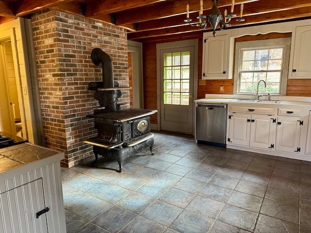 kitchen with sink, white cabinets, stainless steel dishwasher, and beamed ceiling