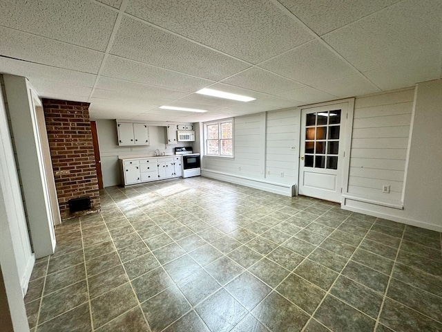 basement featuring baseboard heating, sink, and a drop ceiling