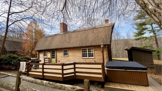 back of property with a wooden deck and a hot tub