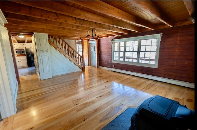 unfurnished living room with a notable chandelier, beamed ceiling, wooden walls, wood ceiling, and baseboard heating