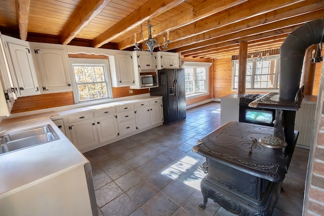 kitchen featuring wood ceiling, white cabinets, beam ceiling, and stainless steel microwave