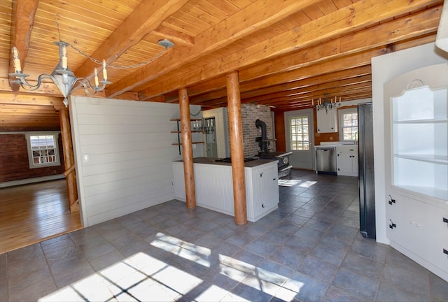 kitchen with pendant lighting, white cabinets, dishwasher, beamed ceiling, and a wood stove