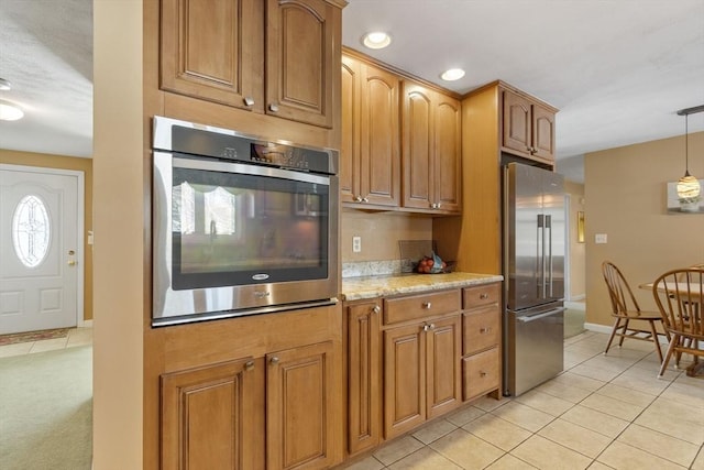 kitchen featuring light stone counters, stainless steel appliances, hanging light fixtures, and light tile patterned floors