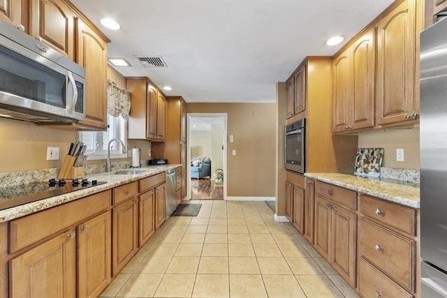 kitchen featuring light stone countertops, light tile patterned floors, stainless steel appliances, and sink