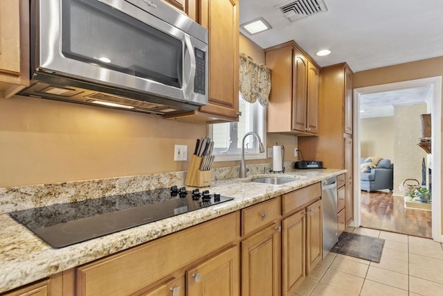 kitchen featuring appliances with stainless steel finishes, sink, light tile patterned floors, and light stone counters