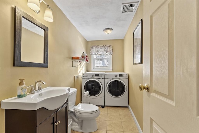 clothes washing area featuring light tile patterned floors, sink, and washing machine and clothes dryer