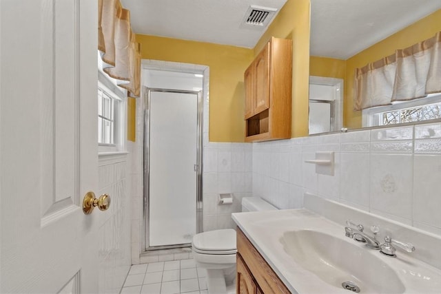 bathroom featuring tile walls, a shower with door, tile patterned floors, and toilet