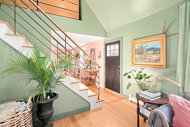 foyer with stairs, wood finished floors, a baseboard radiator, high vaulted ceiling, and baseboards
