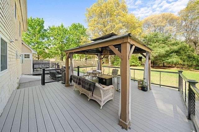 wooden deck featuring a gazebo, a lawn, and view of scattered trees