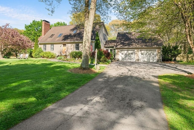 new england style home with asphalt driveway, a front yard, and a chimney