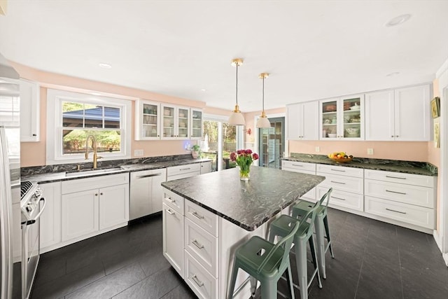kitchen with stainless steel appliances, dark tile patterned flooring, a sink, a kitchen breakfast bar, and recessed lighting