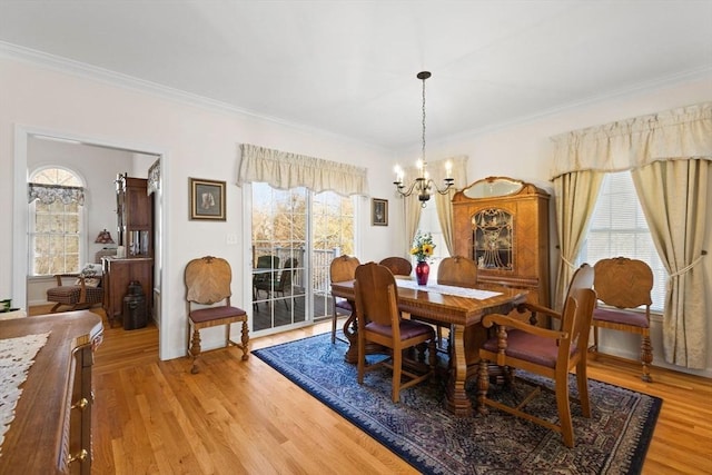 dining area with light wood-type flooring, crown molding, and a healthy amount of sunlight