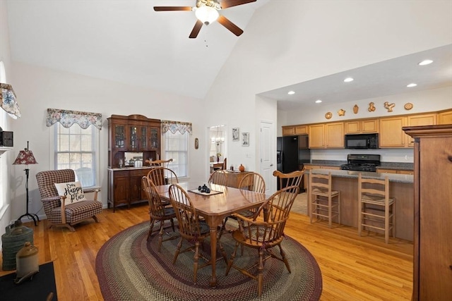 dining room featuring ceiling fan, high vaulted ceiling, and light wood-type flooring