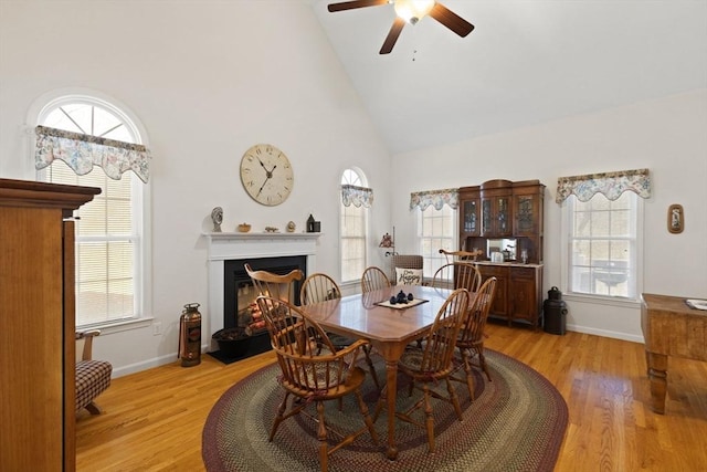 dining room featuring light wood-type flooring, high vaulted ceiling, ceiling fan, and a healthy amount of sunlight