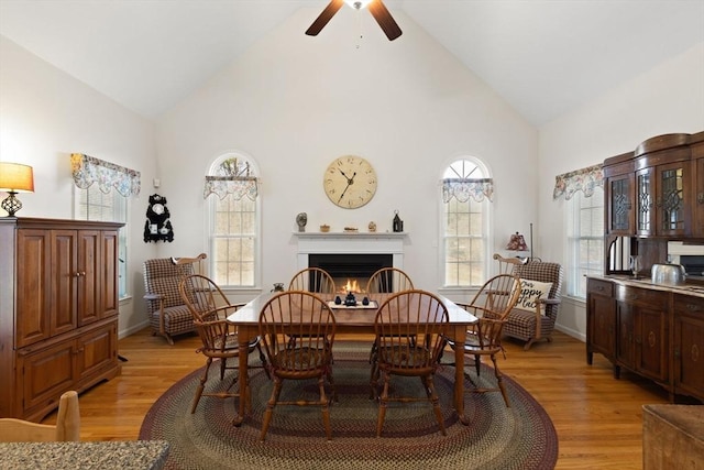 dining area featuring light wood-type flooring, high vaulted ceiling, and ceiling fan