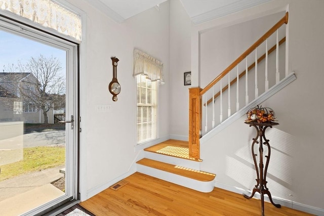 foyer entrance with crown molding and hardwood / wood-style floors