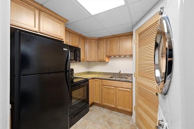 kitchen with sink, a paneled ceiling, dark stone counters, and black appliances