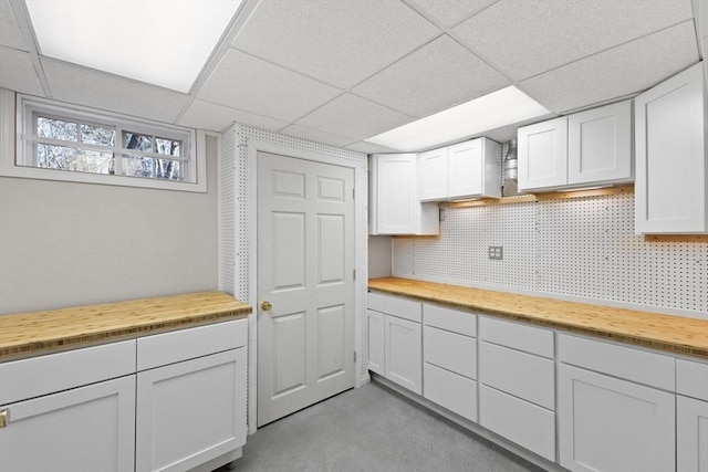 kitchen with butcher block counters, white cabinetry, and tasteful backsplash