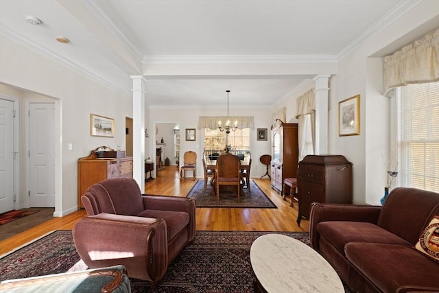 living room with a chandelier, light wood-type flooring, ornate columns, and ornamental molding