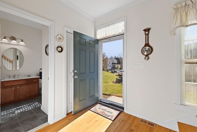 entrance foyer with crown molding, light hardwood / wood-style flooring, and sink