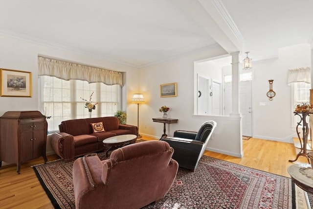 living room featuring light wood-type flooring, crown molding, and ornate columns