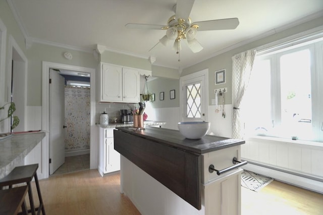 11 Dallas St, Worcester, MA 01604 - kitchen featuring light wood-style flooring, white cabinets, ceiling fan, ornamental molding, and dark countertops