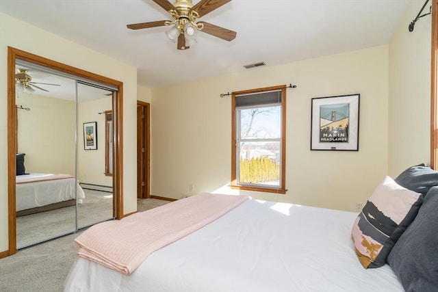 bedroom with a baseboard heating unit, light carpet, ceiling fan, and a closet