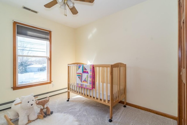 carpeted bedroom featuring a nursery area and ceiling fan