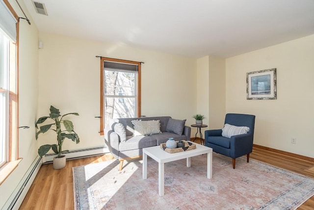 living room featuring baseboard heating and light hardwood / wood-style flooring