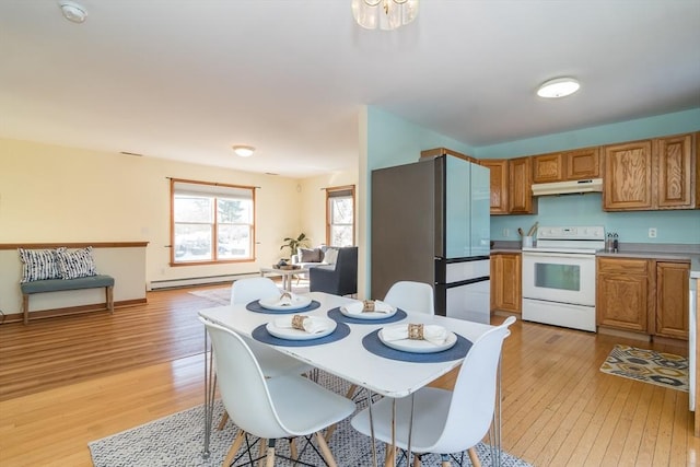 kitchen featuring white electric stove, a baseboard heating unit, stainless steel refrigerator, and light hardwood / wood-style floors