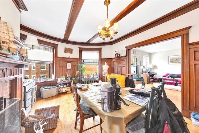 dining room featuring a chandelier, light wood-style flooring, crown molding, and a decorative wall