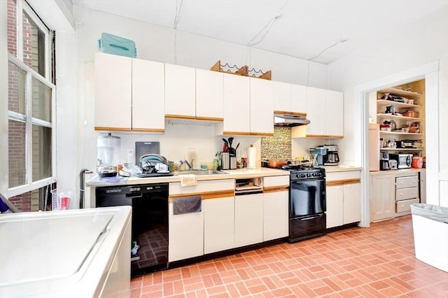 kitchen featuring black appliances, under cabinet range hood, a sink, brick patterned floors, and light countertops
