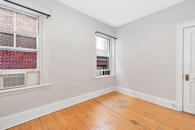 empty room featuring baseboards, wood-type flooring, and cooling unit