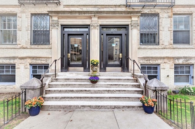 entrance to property featuring fence and brick siding