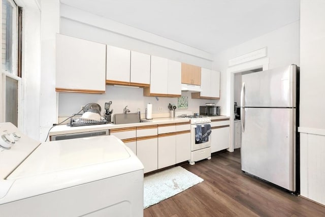 kitchen with freestanding refrigerator, gas range gas stove, under cabinet range hood, a sink, and dark wood-style floors