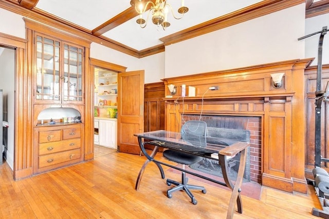office area featuring crown molding, a chandelier, light wood-style flooring, and a fireplace